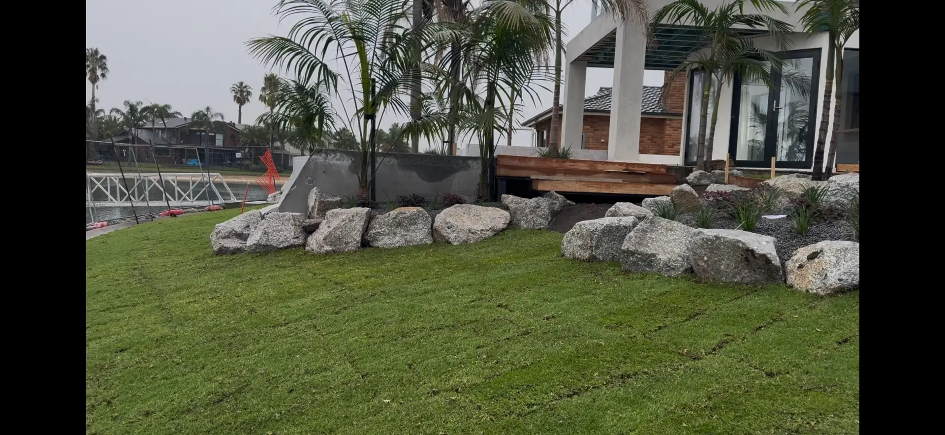 Fresh turf laid with granite boulder edging along waterfront property