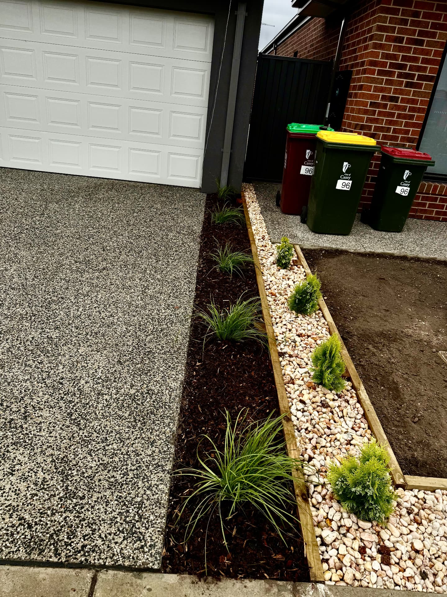 Driveway edge garden with mulch, ornamental grasses and pebble strip