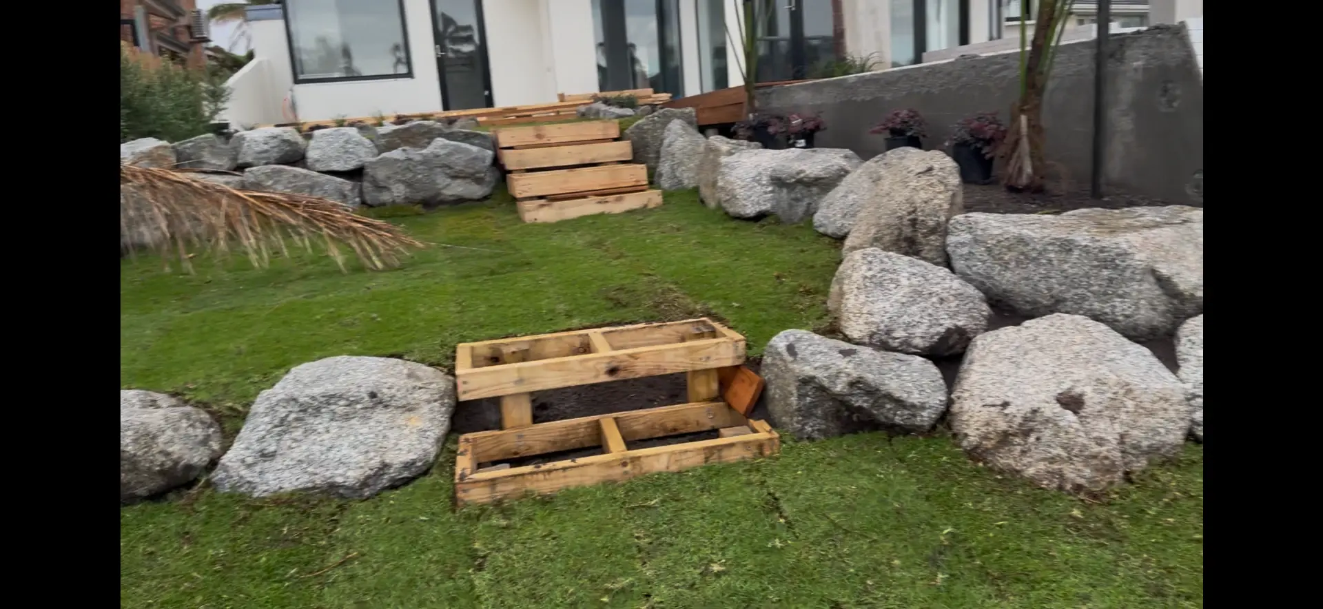 Boulder garden bed with timber steps and freshly laid turf