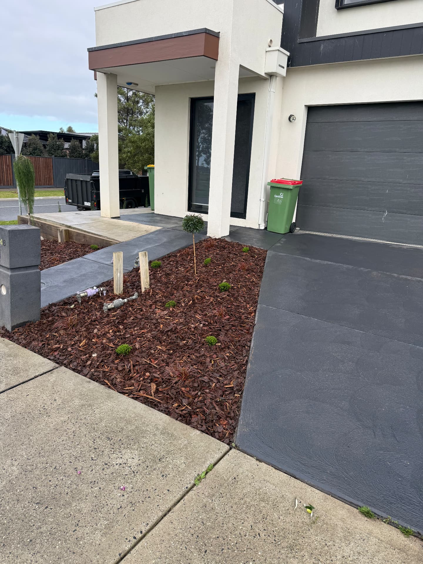 Mulched garden bed with new plantings beside driveway